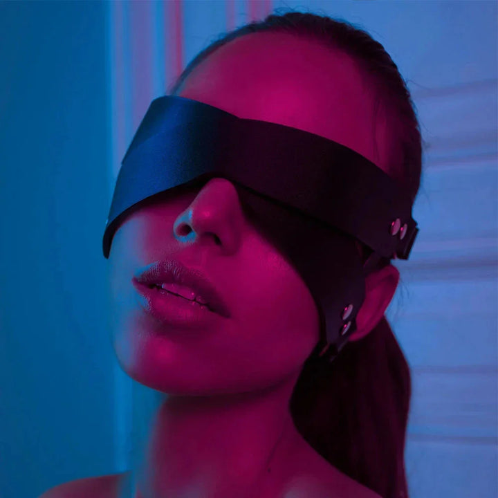 Woman wearing black leather blindfold mask from ghalas under blue and pink lighting