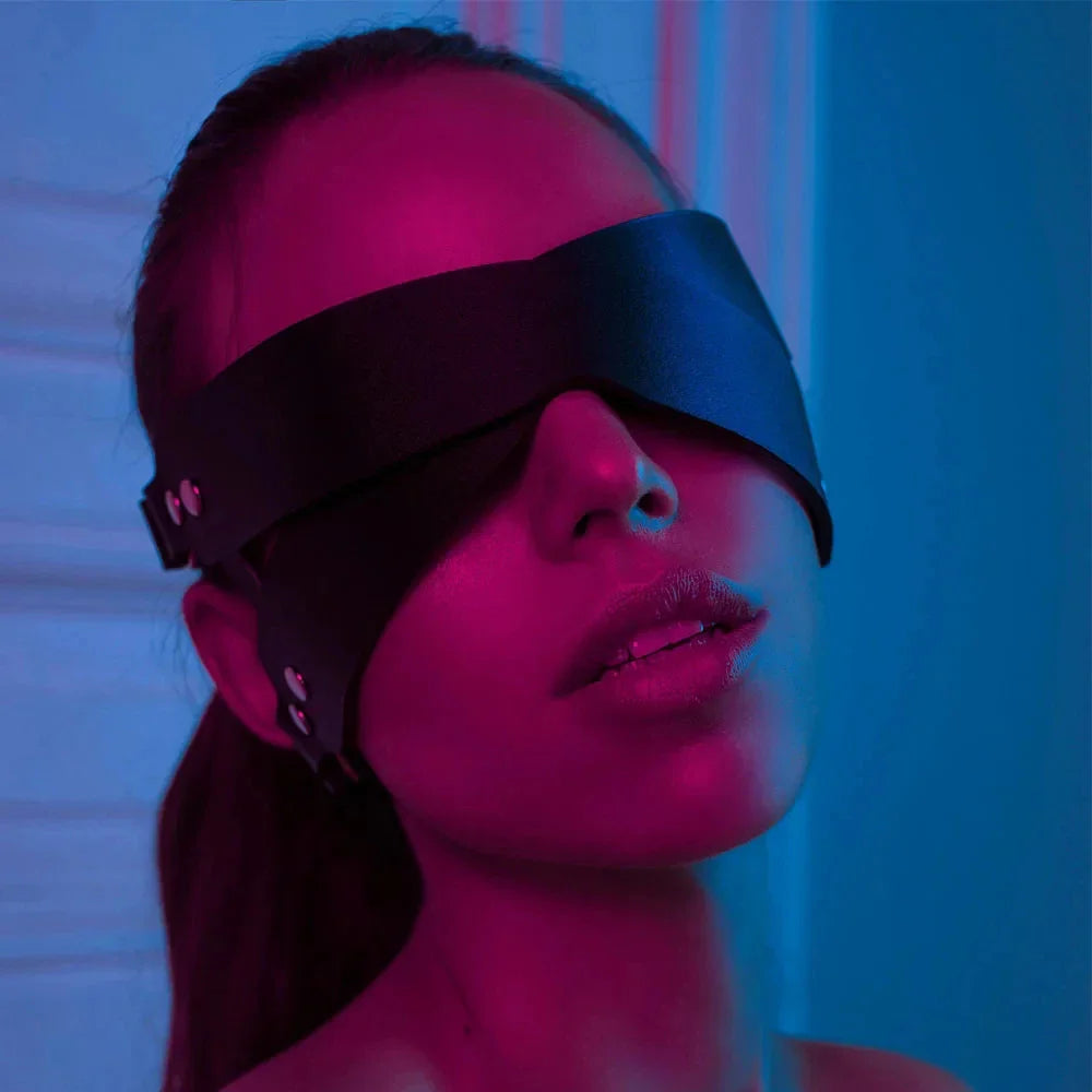 Ghalas black leather blindfold mask worn by woman in moody pink and blue lighting