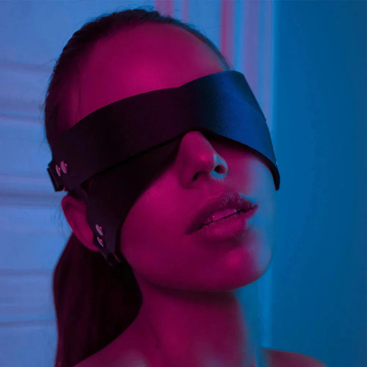 Ghalas black leather blindfold mask worn by woman in moody pink and blue lighting