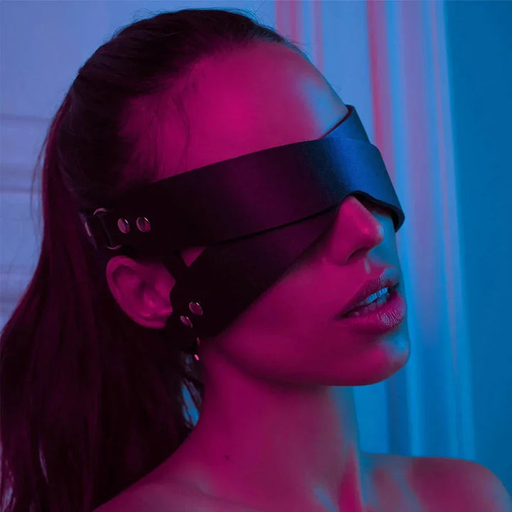 Woman wearing a black leather blindfold mask by ghalas under pink and blue lighting
